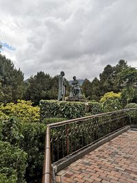 Low angle view of statue against trees and plants against sky