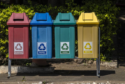 Four color trash cans for recycling, with the words plastic, paper, glass and metal in brazil