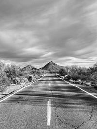Road leading towards mountains against sky