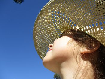 Low angle view of girl wearing straw hat against clear blue sky on sunny day