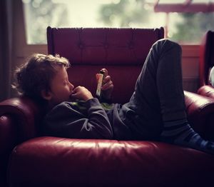 Young woman using phone while sitting on sofa at home