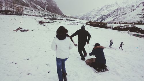 People standing on snow covered mountain against sky
