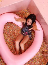 High angle view of woman with heart shape inflatable ring and confetti