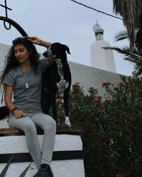 Woman with dog sitting against built structure