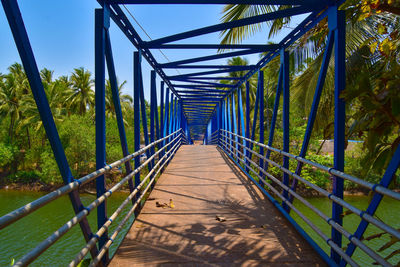 Footbridge amidst trees against sky