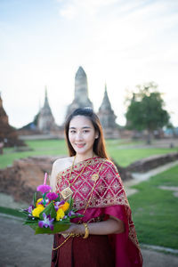 Portrait of smiling young woman standing against plants