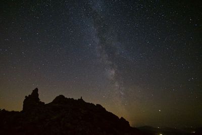 Low angle view of silhouette mountain against sky at night