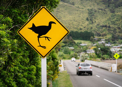 Arrow sign on road amidst trees