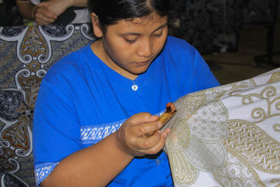 Close-up of girl looking away while sitting against blue wall