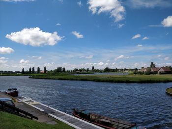 Scenic view of river by buildings against sky