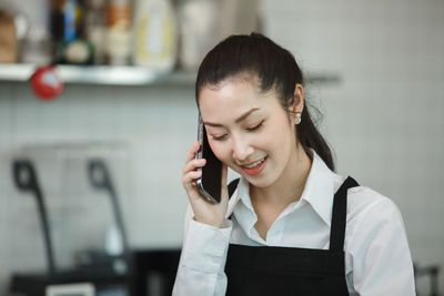 Side view of young woman using mobile phone in cafe