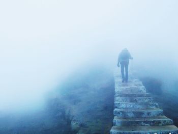 Rear view of hiker climbing steps at sandakphu in foggy weather