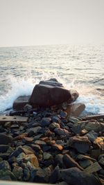 Pebbles on beach against clear sky