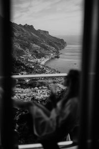 Rear view of man photographing sea against sky