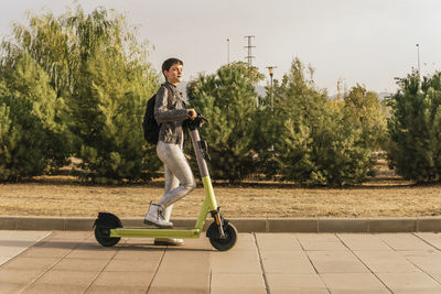 Woman with electric scooter walking on footpath