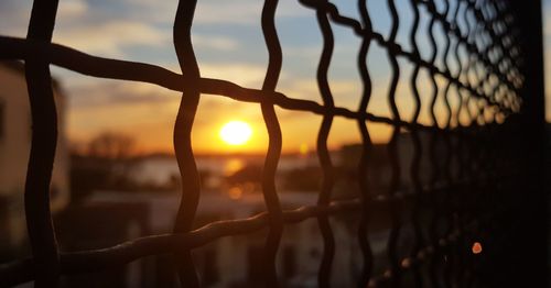 Close-up of silhouette fence against sunset sky