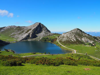 Scenic view of lake by mountains against blue sky