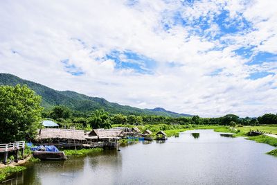 Scenic view of river by buildings against sky