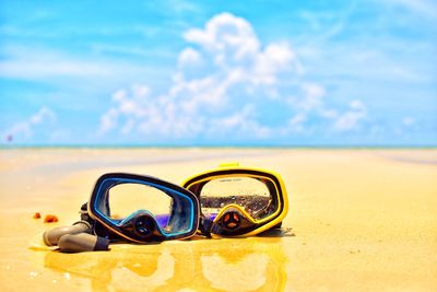 Scuba masks at beach against sky