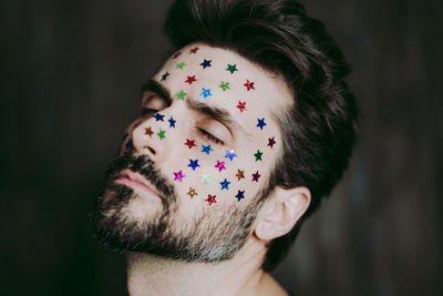Close-up of man with star shape stickers on face