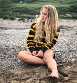 Beautiful young woman sitting on land