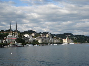 City at waterfront against cloudy sky