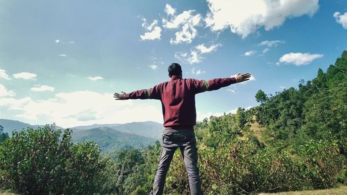 Rear view of man standing on mountain against sky