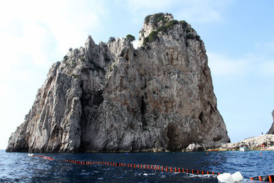 Rock formation by sea against sky