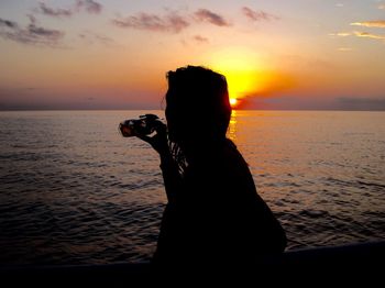 Silhouette woman on beach against sky during sunset