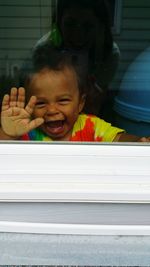 Portrait of cute boy laughing seen through window