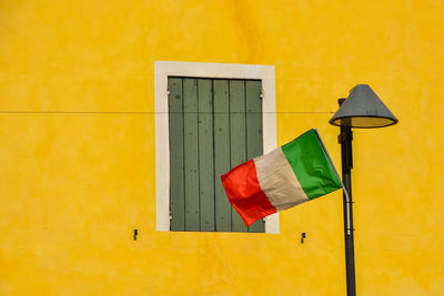 Low angle view of flag against yellow wall