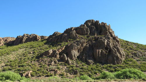 Rock formations on mountain against clear blue sky