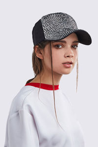 Portrait of young woman wearing hat against white background