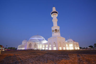 Illuminated building against clear blue sky