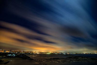 Scenic view of beach against dramatic sky during sunset