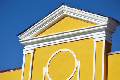 Low angle view of yellow building against clear blue sky