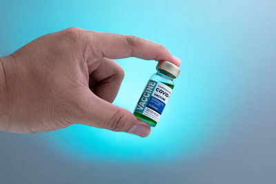 Midsection of person holding camera against blue background