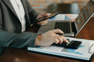 Midsection of man using mobile phone on table