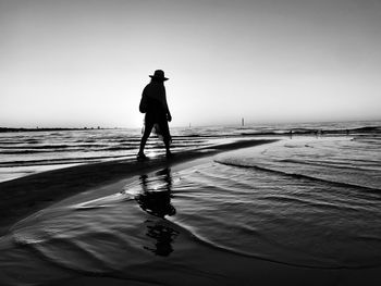 Rear view of silhouette woman standing at beach against sky