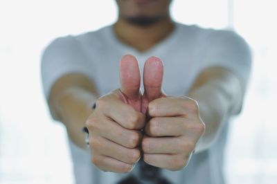 Midsection of man showing thumbs up