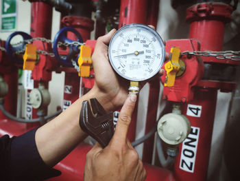 Cropped hands of man holding pressure gauge