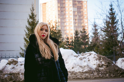 Portrait of woman in warm clothing against buildings