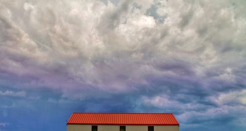 Low angle view of cottage roof against cloudy sky