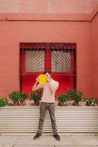Portrait of young man standing against red wall