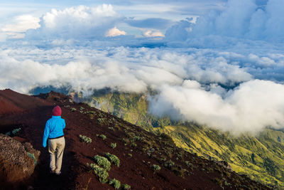 Rear view of man walking on mountain against sky