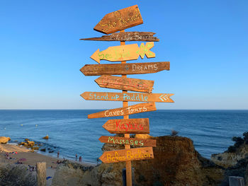 Information sign on beach against clear sky