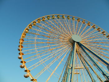 Low angle view of ferris wheel against clear blue sky