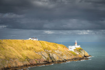 Lighthouse by sea against sky