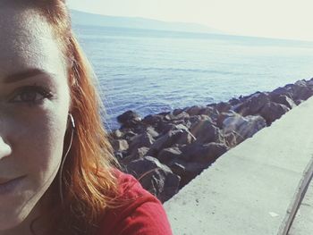 Close-up portrait of woman by sea against sky