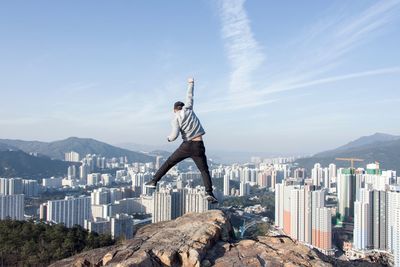 Man jumping against cityscape